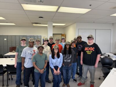 A group of students pose wearing camo Laborup ball caps.
