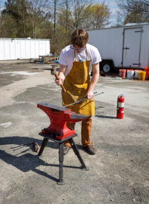 Justin Pavlov hammers a piece of metal on an anvil.