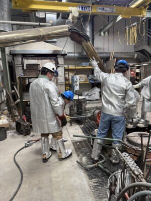 Bootcamp participants pour molten aluminum into molds.