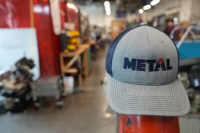 A METAL hat sitting on a piece of equipment in a metal shop.